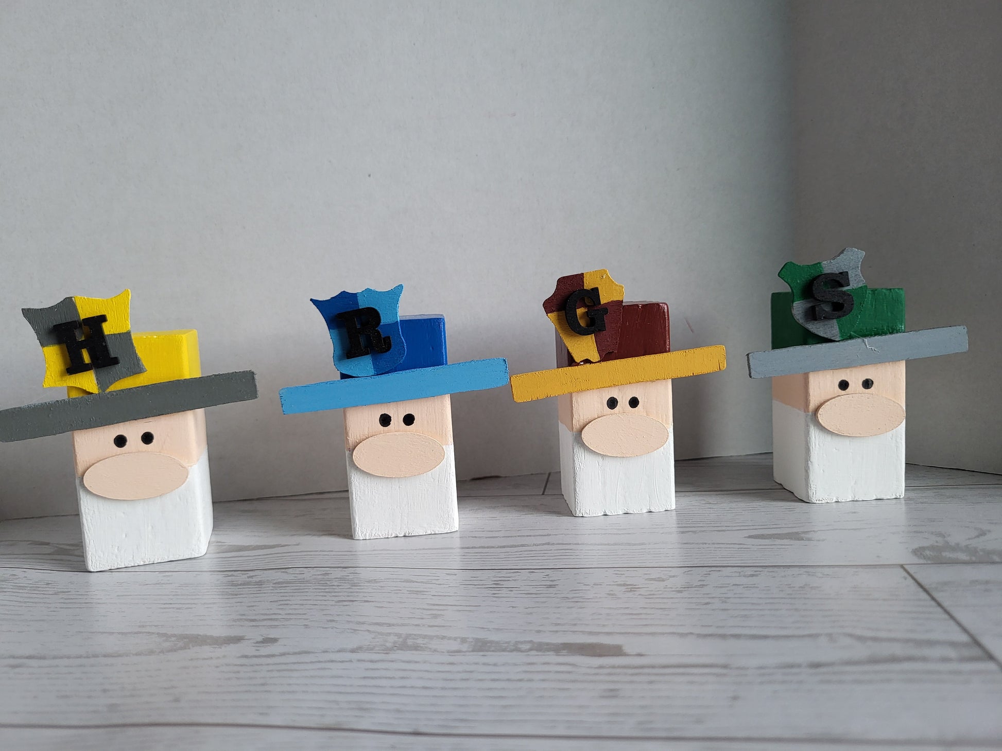Four handmade wooden gnomes hand-painted with the Houses of Hogwarts colors